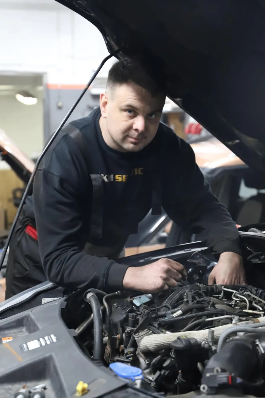 Mechanik KM Service pracujący przy silniku samochodu